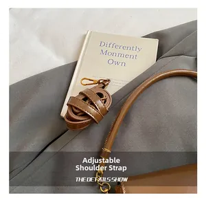 Detail of adjustable brown leather shoulder strap with elegant gold metal buckle closure