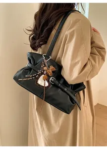 Détail du sac sous le bras en similicuir noir avec texture plissée et breloque