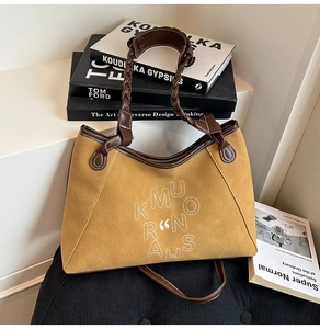 Detail of the vintage suede tote bag showing embroidery and woven handle textures
