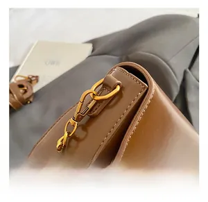 Detail shot of brown matte leather handbag with gold metal hook and fine stitching
