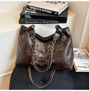 Detailed macro view of dark brown tote bag with white contrast stitching and woven handles