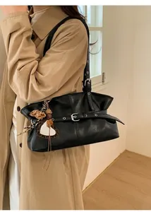Vue détaillée du sac à bandoulière en cuir ciré noir avec boucles et breloque en cœur