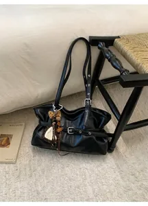 Détail du sac à main noir en cuir ciré avec boucle élégante et breloque léopard à glands