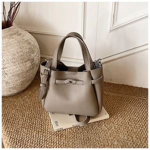 Detail of taupe litchi leather bucket bag with silver twist lock and adjustable strap
