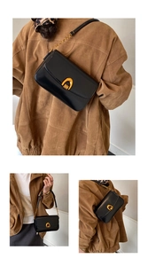 Detail view of black leather shoulder bag showing elegant gold arch-shaped buckle hardware