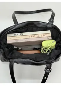 Vue détaillée de l'intérieur du grand sac à main en cuir ciré noir avec livres et objets