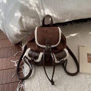 Detail of dark brown plush backpack with faux shearling trim and drawstring buckle closure