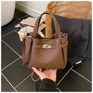 Close-up of brown litchi pattern leather handbag with silver metal turn-lock buckle
