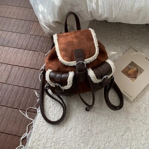 Close-up of retro brown suede backpack with white plush faux fur trim and metal buckles