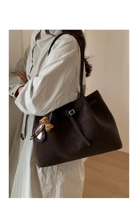 Detail view of large dark coffee tote bag with decorative buckle and leopard print charm