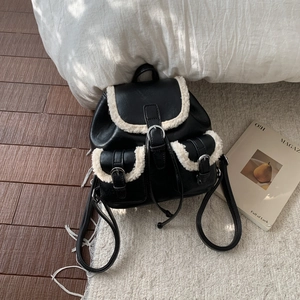 Detail of vintage black leather backpack with fuzzy fleece trim and front buckle pockets