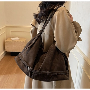 Detail of dark brown suede tote bag with strap buckle and soft textured finish