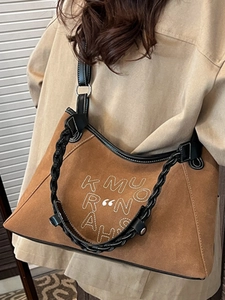 Brown suede tote bag with woven leather strap and embroidered logo on model shoulder