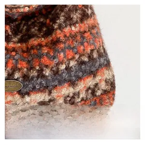 Nahaufnahme von buntem Bouclé-Stoff mit einem bronzefarbenen Handmade-Metallemblem