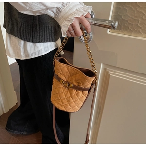 Détail d'un sac seau matelassé marron caramel avec chaîne dorée et fermoir rotatif