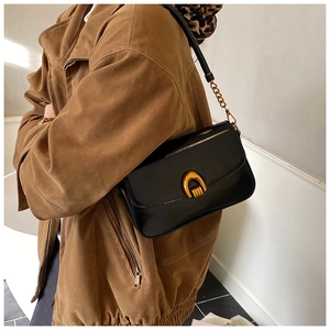 Detail of elegant black leather underarm bag featuring a vintage gold horseshoe buckle