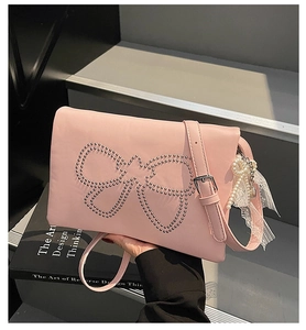 Detail of pink shoulder bag with silver rivet bow pattern and pearl lace charm