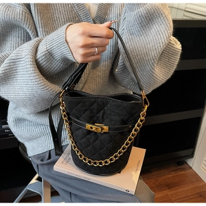Détail du sac seau en velours noir matelassé avec boucle dorée et bandoulière en chaîne