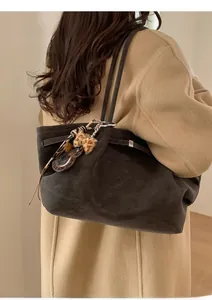 Detail of a large dark brown suede tote bag featuring a cute leopard print bear charm
