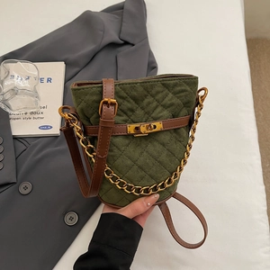 Gros plan d'un sac seau matelassé vert foncé avec chaîne dorée et fermoir pivotant