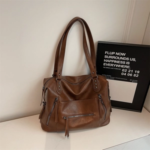 Detail shot of the large brown tote bag showing textured PU leather and metal zipper pockets