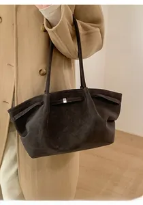 Detail of minimalist dark brown suede tote bag with silver buckle worn with a coat