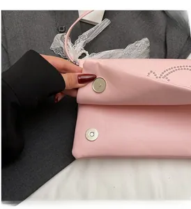Detail view of pink square bag with heart rivets and magnetic clasp showing metallic texture