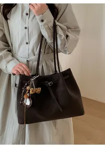 Detail of dark brown leather tote bag with unique leopard print heart charm and metal buckle