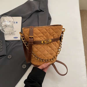 Vue détaillée du sac seau en daim matelassé marron avec fermoir tournant doré et chaîne