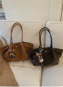 Detail of suede tote bags in caramel and dark coffee with leopard heart pendants