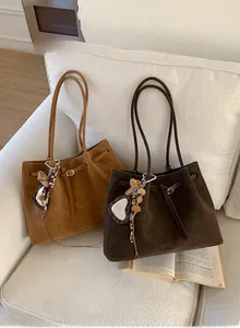 Close-up of vintage brown suede tote bags with heart leopard charm on a white sofa