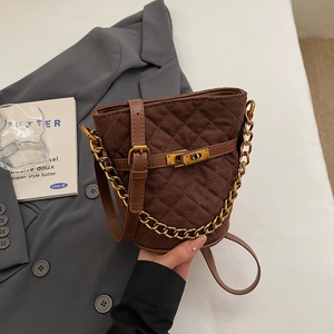 Détail d'un sac seau matelassé marron avec chaîne dorée et boucle métal vintage