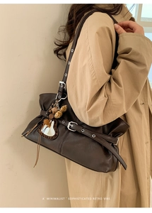 Gros plan d'un sac à bandoulière en cuir marron rétro avec sangles et pendentifs déco