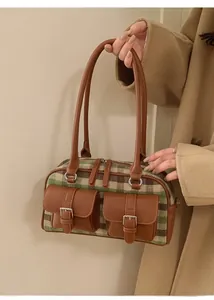 Close-up of green checkered Boston bag featuring premium leather pockets and metal buckles