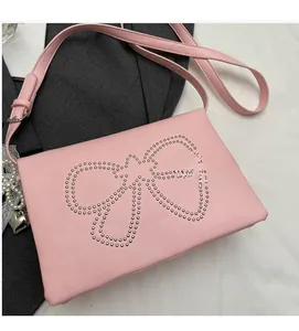 Detail view of light pink square crossbody bag with silver studs bow and pearl charms