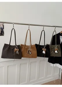 Detailed view of four suede tote bags in brown, black and olive with decorative charms