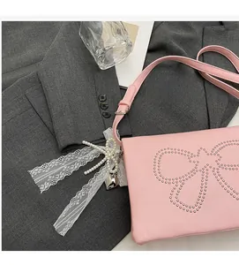 Detail of pink PU leather square bag featuring metallic stud bow and lace pearl pendant