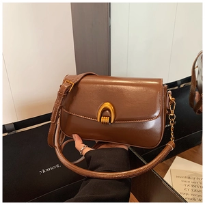 Detail of vintage brown leather handbag with elegant gold U-shaped metal buckle closure