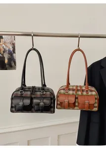 Detail of plaid canvas shoulder bags with leather trim and decorative metal buckles