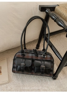 Close-up of retro plaid fabric and leather pockets on a large capacity shoulder bag