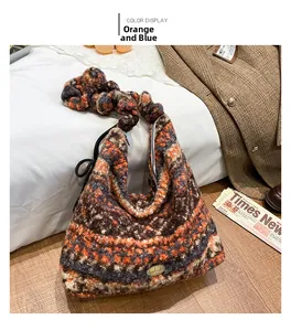 Detail der Hobo-Tasche mit orange-blauer Strickstruktur und Handmade-Metallemblem