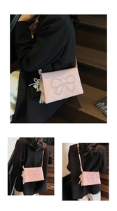 Detail of pink crossbody bag with stud bow pattern, pearl and lace bow charm detail