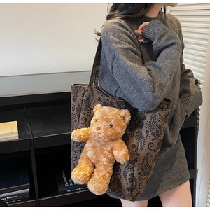 Dettaglio della borsa tote paisley marrone con ciondolo a forma di orsetto e manici robusti