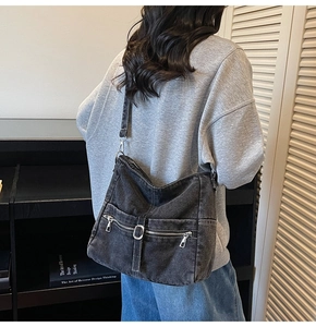 Model view of large dark denim hobo bag featuring zip pockets and silver hardware