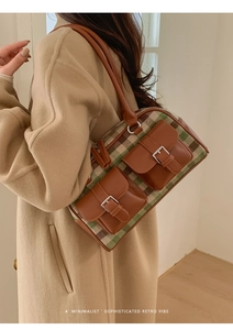 Close-up of retro green plaid Boston bag with brown faux leather trim on a camel coat