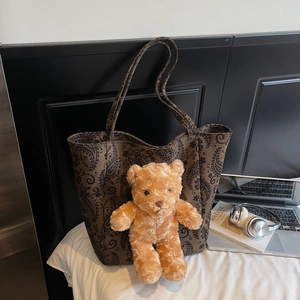 Dettaglio della borsa tote in tela marrone con motivo paisley e charm a orsetto