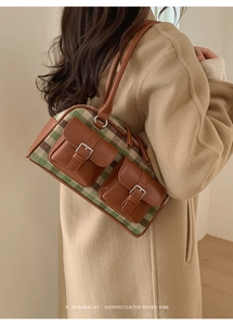 Close-up of retro plaid Boston bag with brown leather pockets and silver metal buckles