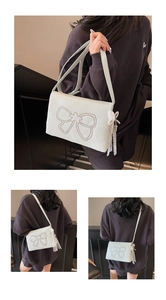 Detail of white crossbody bag featuring silver stud bow and lace pearl charms
