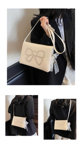 Detail showing the cream leather shoulder bag with silver rivet bow and lace pearl charms