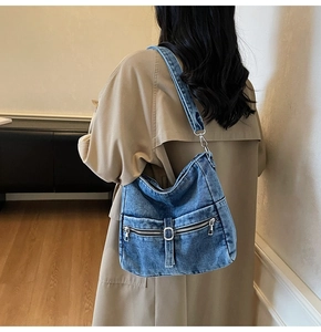 Side view of large denim tote bag with metal zipper and buckle detail on a model
